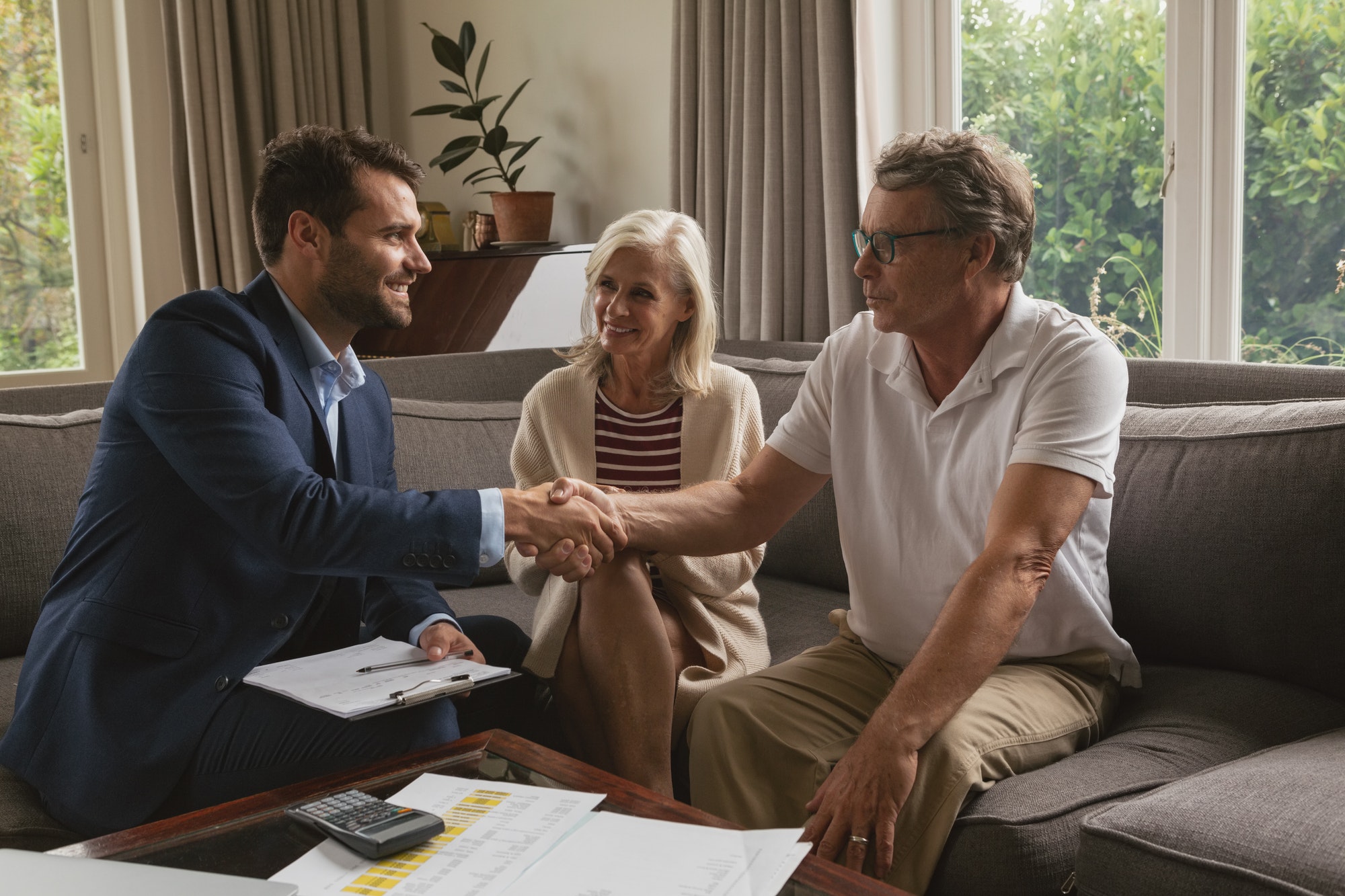 Active senior Caucasian man shaking hands with real estate agent in living room at home