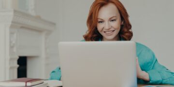 Focused cheerful redhead successful businesswoman does research, makes business project