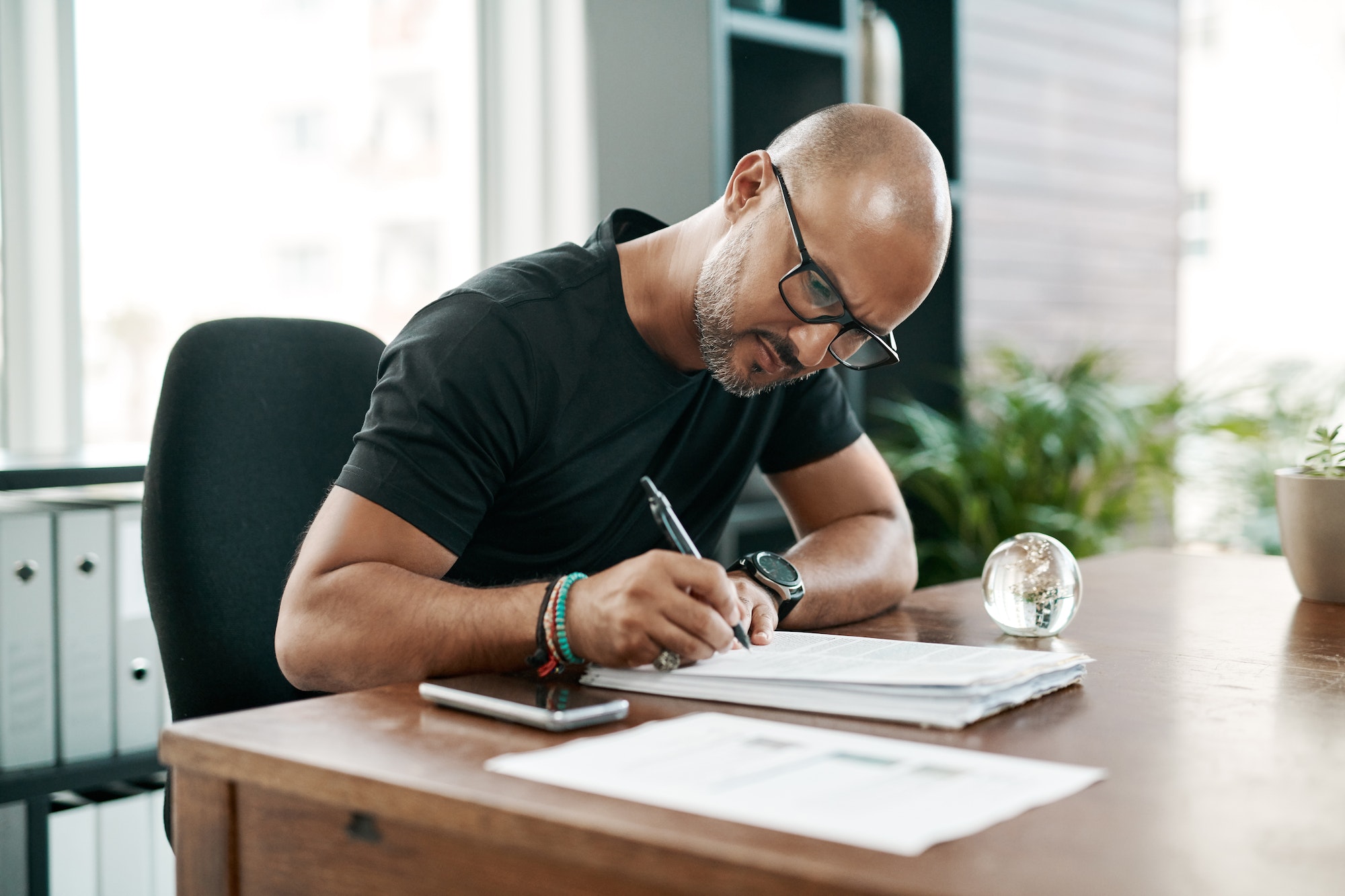 Shot of a mature businessman filling out paperwork at his desk in a modern office