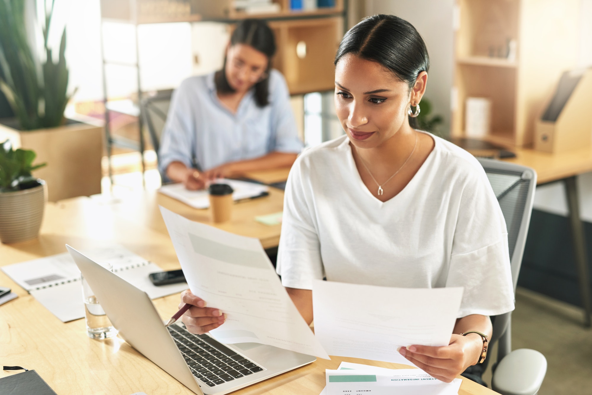 Taking my time to be thorough. Shot of a young businesswoman reviewing paperwork at work.