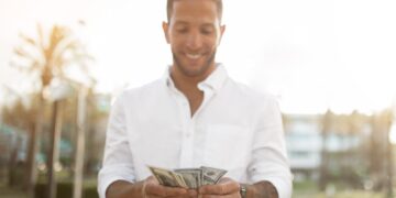 First salary. Happy young businessman holding fan of money, celebrating financial luck and success