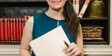 a woman in blue sleeveless shirt smiling at the camera