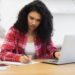 Woman working on assignments at home while using a laptop on a desk